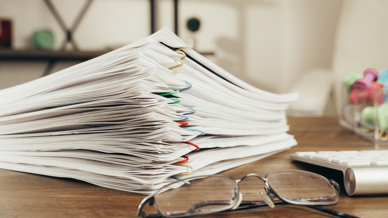 Stack of papers beside a pair of glasses